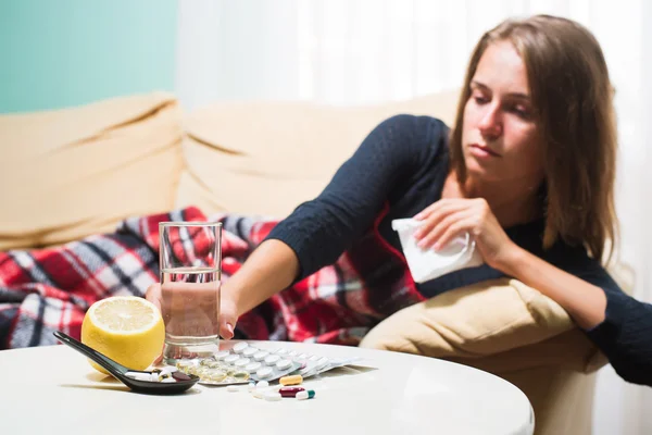 Zieke vrouw liggend op de Bank onder wollen deken niezen en het vegen van de neus. Gevangen koud — Stockfoto