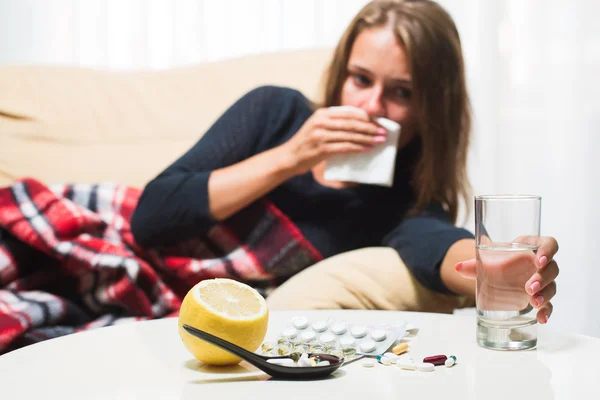 Zieke vrouw liggend op de Bank onder wollen deken niezen en het vegen van de neus. Gevangen koud — Stockfoto