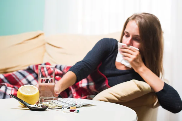 Wanita sakit berbaring di sofa di bawah selimut wol bersin dan menyeka hidung. Tertangkap dingin — Stok Foto