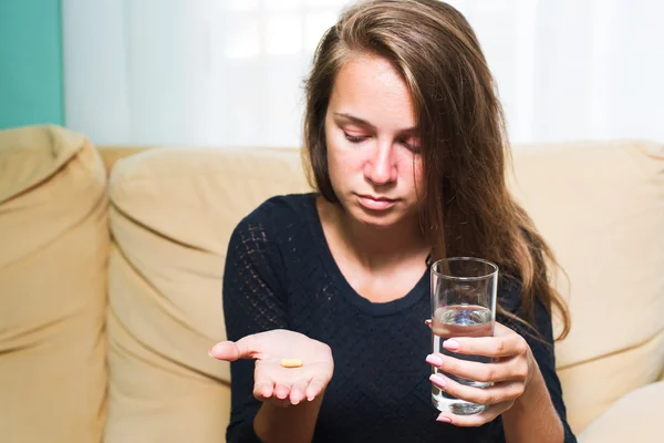 Sjuk kvinna Holding piller och glas vatten — Stockfoto