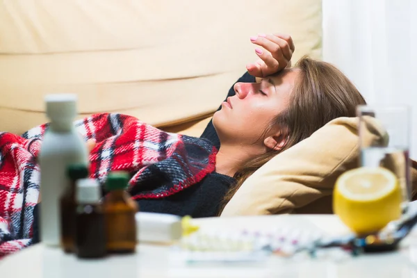 Άρρωστη γυναίκα ξαπλωμένο στον καναπέ κάτω από μαλλί κουβέρτα — Φωτογραφία Αρχείου