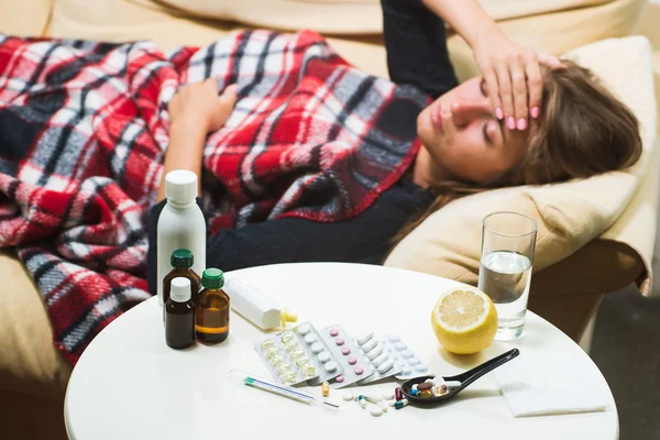 Больная женщина лежит на диване под шерстяным одеялом — стоковое фото