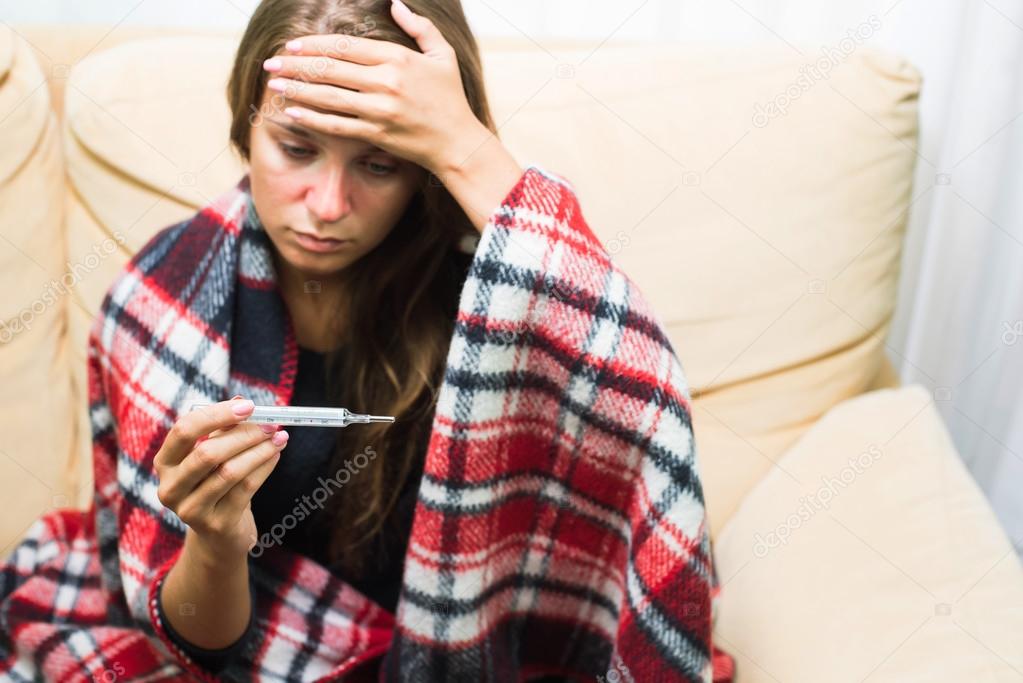 Sick woman looking at thermometer