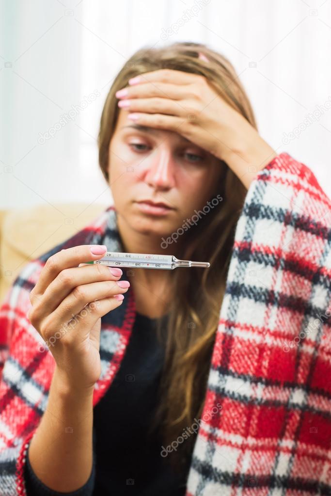 Sick woman looking at thermometer