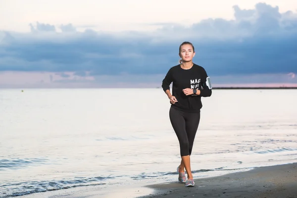 Mujer corriendo en la playa al amanecer — Foto de Stock