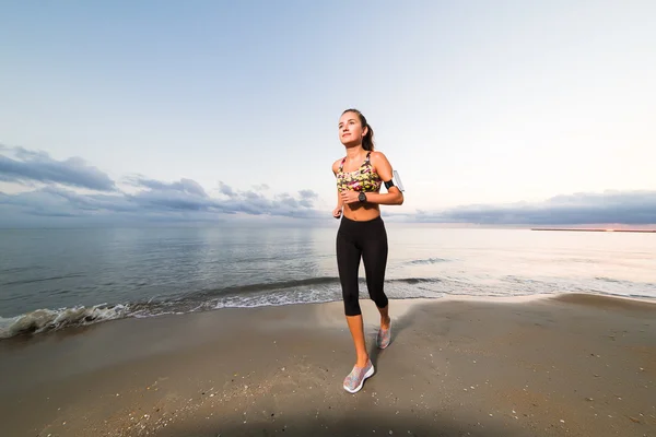 Linda chica en forma corriendo en la playa al amanecer — Foto de Stock