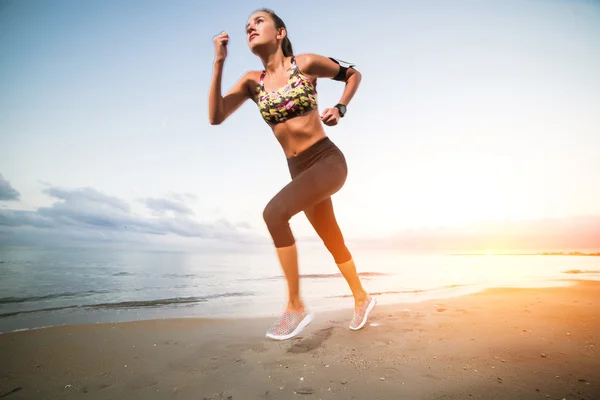 Linda chica en forma corriendo en la playa al amanecer — Foto de Stock