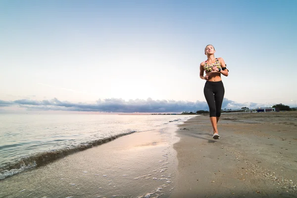 Linda chica en forma trotando en la playa al amanecer — Foto de Stock