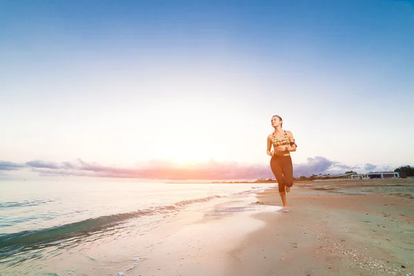 Cute fit girl running on beach at sunrise — Stock Photo, Image