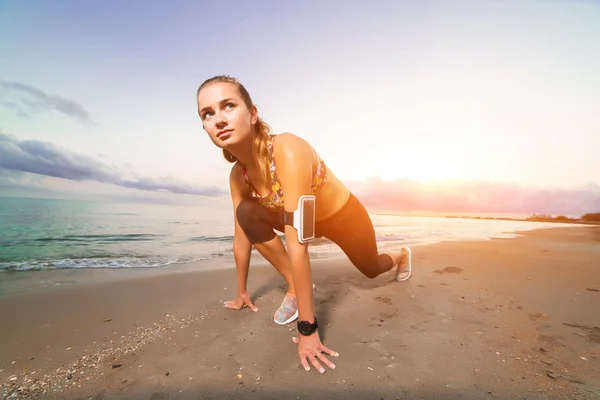 Linda chica en forma comienza a correr en la playa al amanecer — Foto de Stock