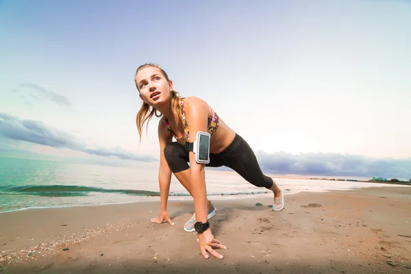 Linda chica en forma comienza a correr en la playa al amanecer — Foto de Stock