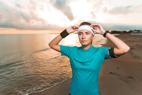 Jeune fille sportive faisant des exercices matinaux sur la plage au lever du soleil — Photo