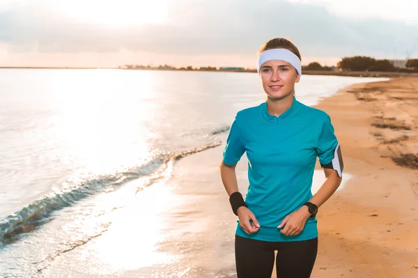 Joven chica deportiva haciendo ejercicios matutinos en la playa al amanecer — Foto de Stock