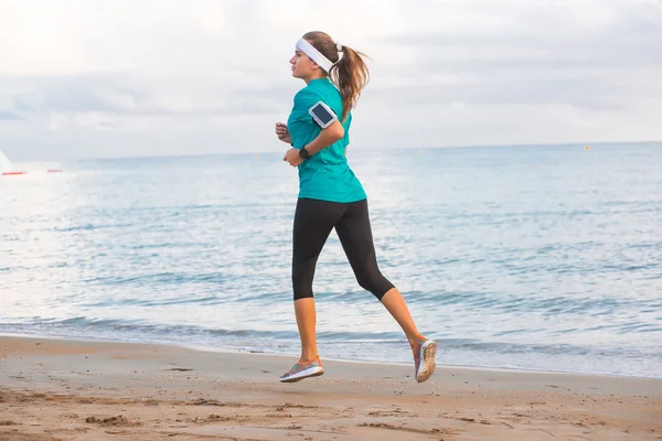 Joven chica en forma corriendo en la playa al amanecer en la mañana — Foto de Stock