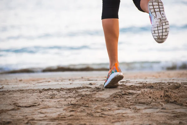 Closeup of female legs running on beach at sunrise in morning — Stock Photo, Image