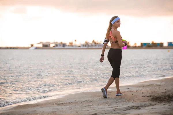 Joven chica en forma corriendo en la playa al amanecer — Foto de Stock