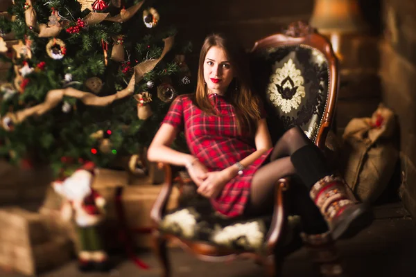 Junges Mädchen sitzt neben Weihnachtsbaum und Geschenken — Stockfoto