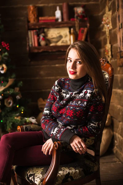 Chica joven sentada junto al árbol de Navidad y regalos — Foto de Stock