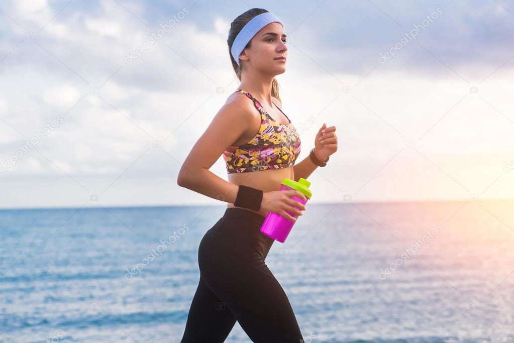 Young fit girl running on beach at sunrise