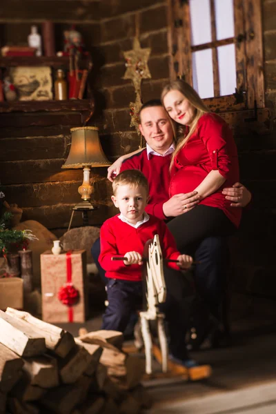 Joven madre embarazada, padre e hijo pequeño celebrando la Navidad en casa —  Fotos de Stock