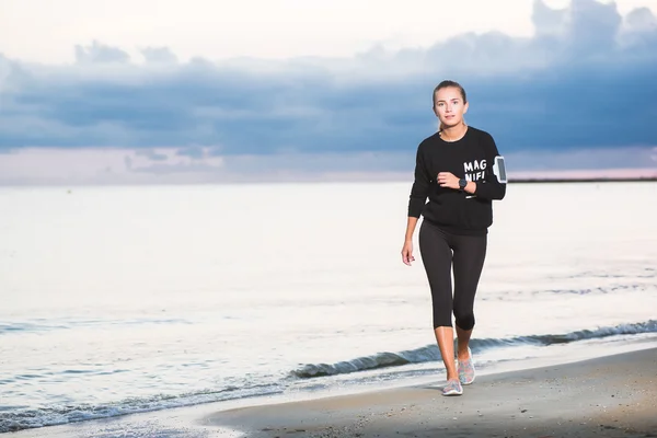 Mujer corriendo en la playa al amanecer — Foto de Stock