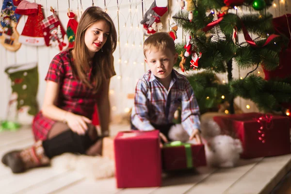 Schwester und kleiner Bruder packen Geschenke vor dem Weihnachtsbaum aus — Stockfoto