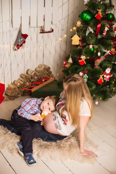 Junge schwangere Mutter und Kind feiern Weihnachten zu Hause — Stockfoto