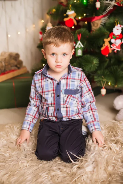 Kleiner Junge sitzt vor dem Weihnachtsbaum — Stockfoto