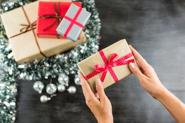 Regalos de Navidad en una mesa con fondo negro y manos sosteniendo presente — Foto de Stock