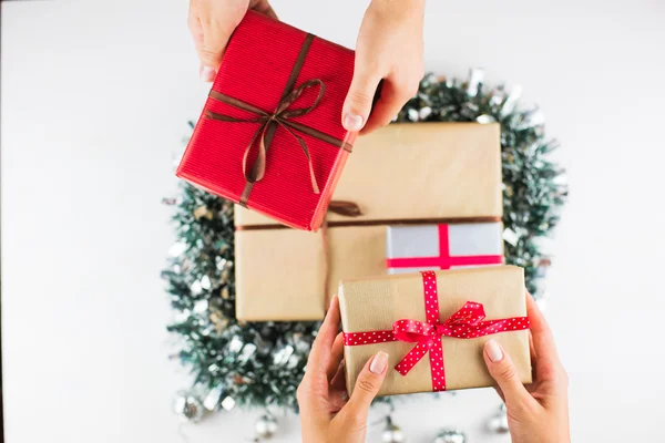 Regalos de Navidad en una mesa con fondo blanco y manos sosteniendo regalos — Foto de Stock