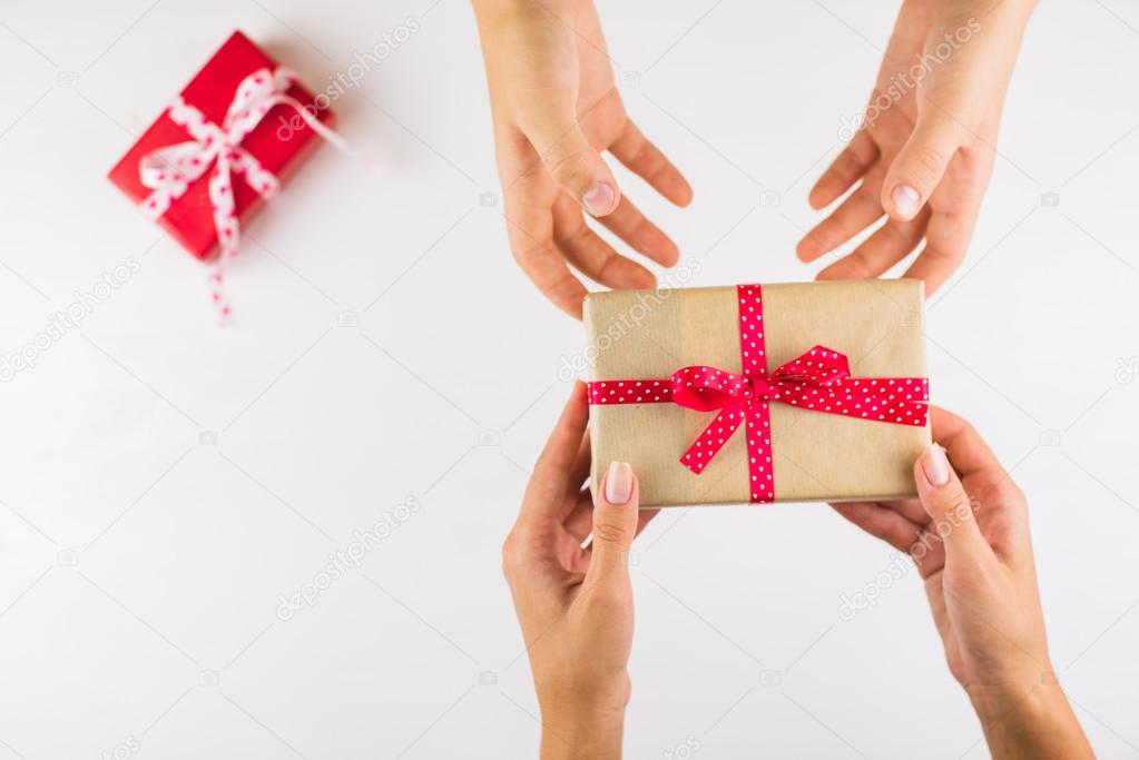 Closeup of hands giving gifts to each other on white background