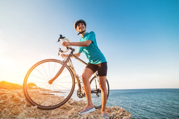 Vrouwelijke fietser staande op een rots en kijken naar zee — Stockfoto