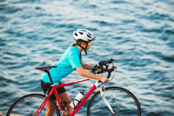 Vrouwelijke fietser staande op een rots en kijken naar zee — Stockfoto