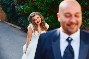 Yeşil çalıların üzerinde gülümseyen bir gelinin portresi.