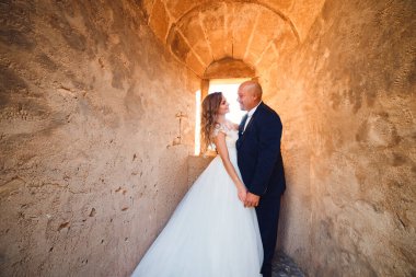 Yeni evliler, kalenin arka planında sarılırlar. geniş açı