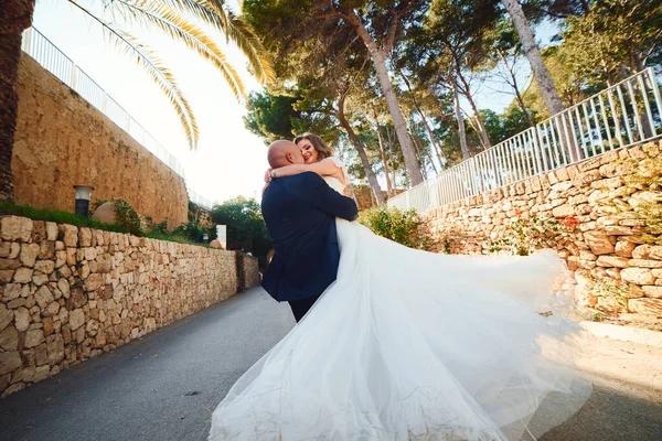石壁やヤシの木を背景に城への入り口で 新婚旅行の抱擁と笑顔 — ストック写真
