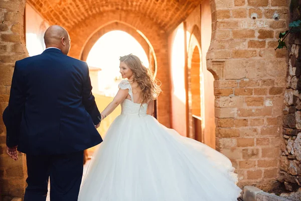 新婚夫婦は城内のアーチを背景に手を取り合う 屋外結婚式 — ストック写真