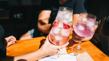 Bir grup arkadaş yaz terasında ellerinde kokteyller ve masada atıştırmalıklarla oturuyorlar.