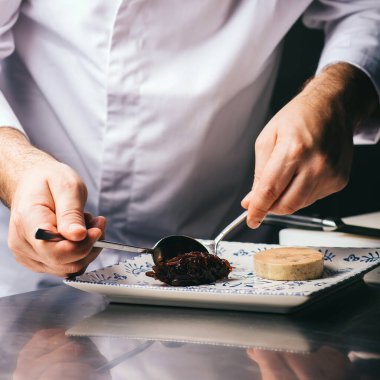 Şef bir tabak kaz ciğeri süslüyor.