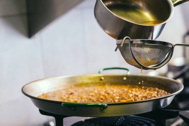 Şef paella 'ya balık çorbası ekliyor. İspanyol yemeği