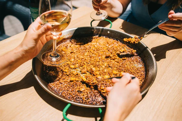 Paella yeme zamanı. Çatal bıçaklı birkaç el, deniz ürünleri ve mürekkep balığı restoranındaki bir masada paella yemeye başlar.