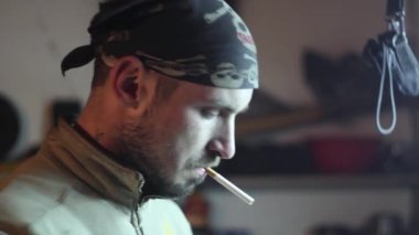 Adam bir sigara içiyor garajda çalışmak için ayarlama.