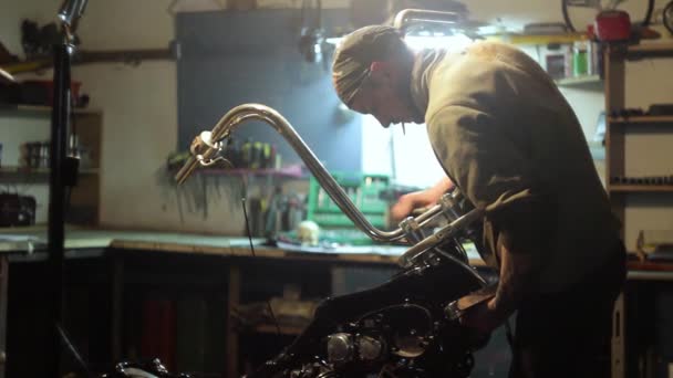 Auto mechanic assembles custom motorcycle in his workshop. — Stock Video