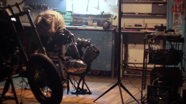Auto mechanic assembles custom motorcycle in his workshop. — Stock Video