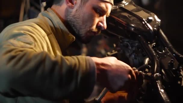 Automonteur assembleert aangepaste motorfiets in zijn atelier. — Stockvideo