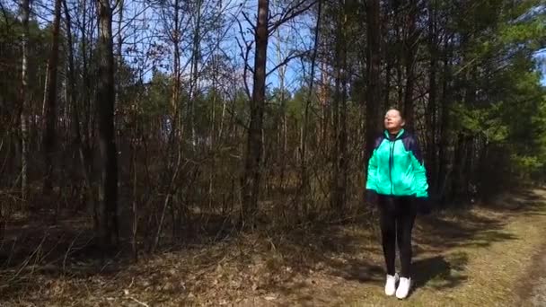 Rijpe vrouw loopt langs een bospad. — Stockvideo