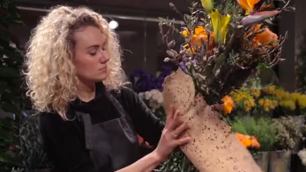 Mooie vrouw bloemist maken een boeket bij bloemenwinkel — Stockvideo