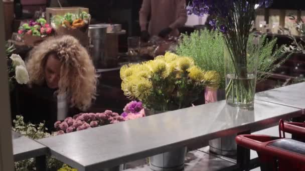 Mulher coloca vaso de flores nas prateleiras florista se prepara para a loja de abertura — Vídeo de Stock