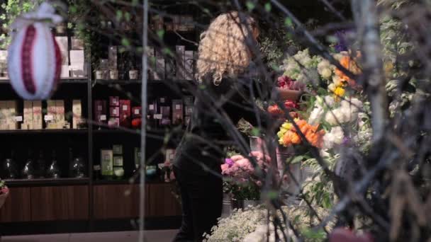 Mulher coloca vaso de flores nas prateleiras florista se prepara para a loja de abertura — Vídeo de Stock
