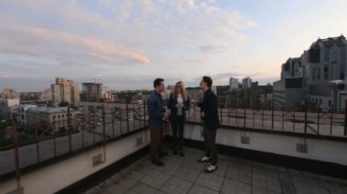 İnsanlar konuşmak ve çatıda bir ofis binası yaz akşamları içme